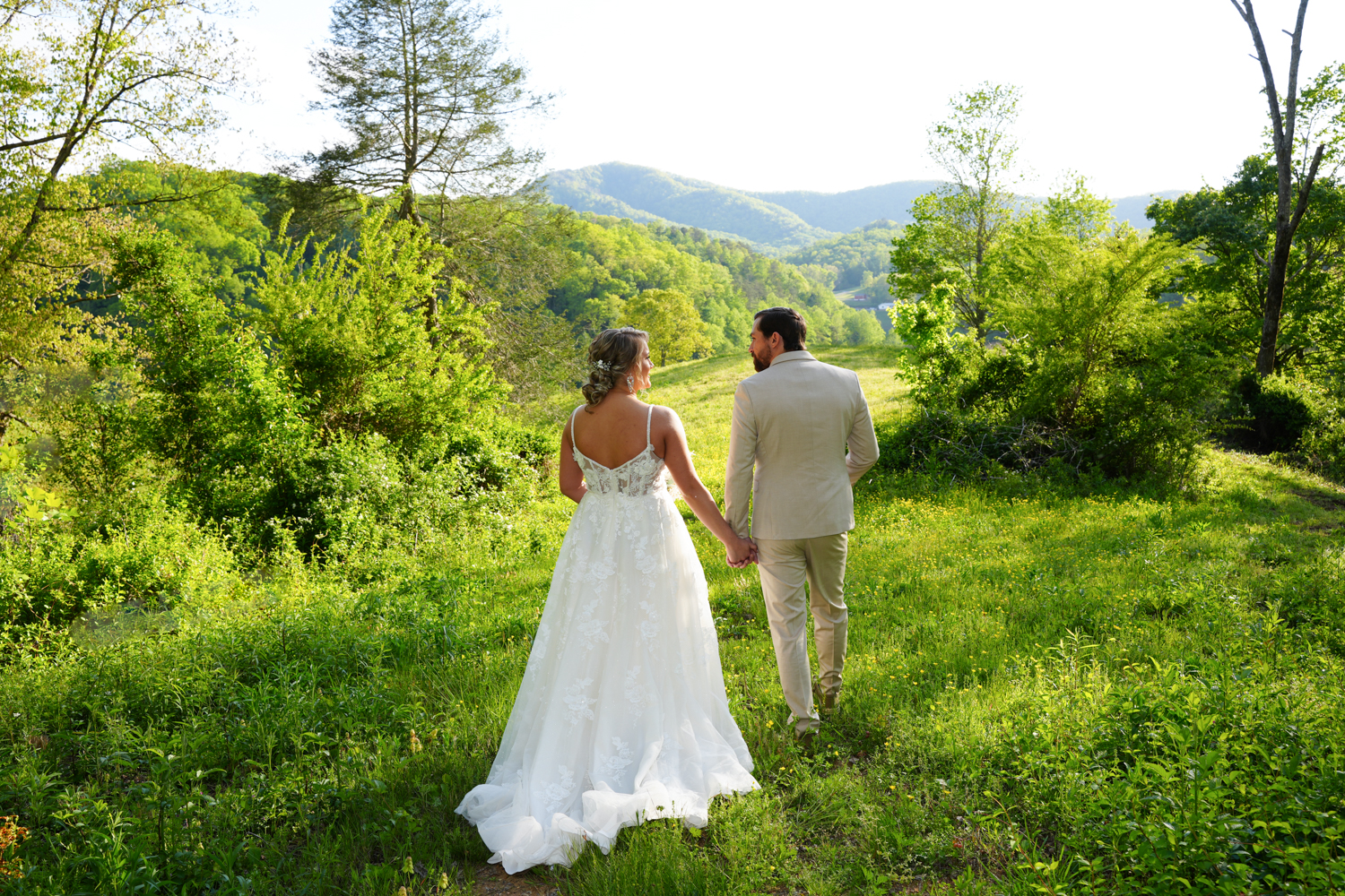 Wedding couple walking through a meadow toward a mountain view at Honeysuckle Hills in Pigeon Forge