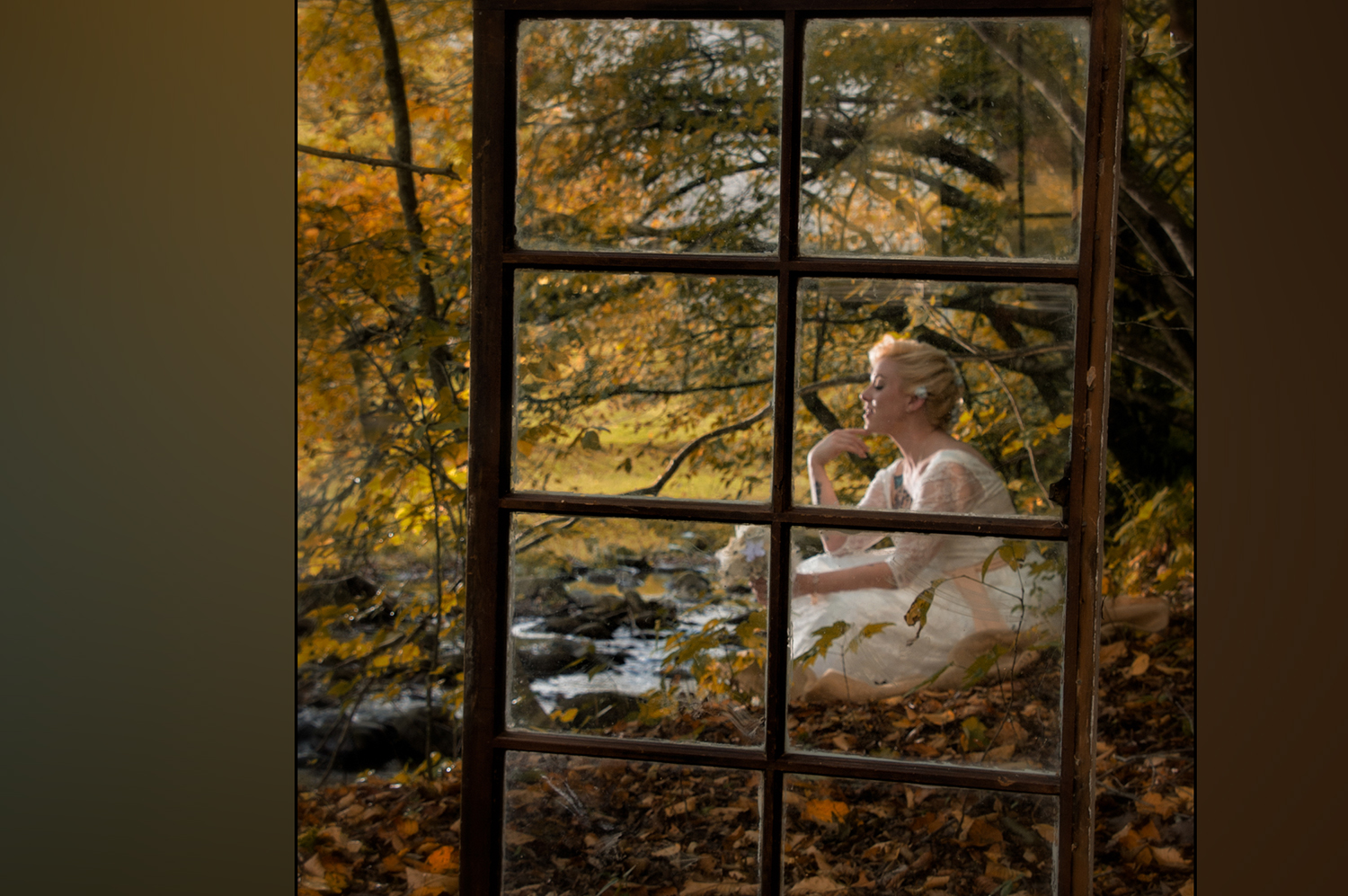 Bride posing in the fall by a creek behind an old window photography prop