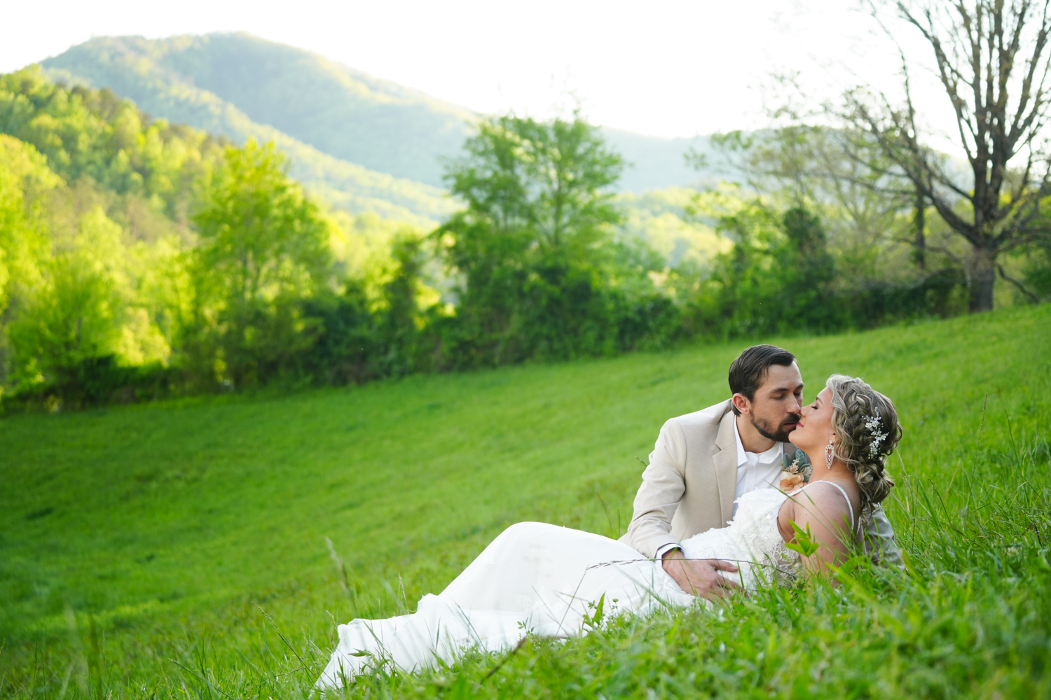 Groom romantically leaning over his bride in a meadow with a mountain view in Pigeon Forge
