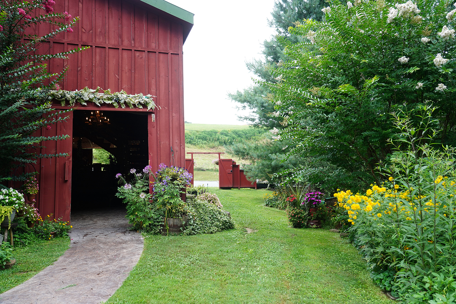 Red barn wedding venue exit with pathway in a summer flower garden at Honeysuckle Hills