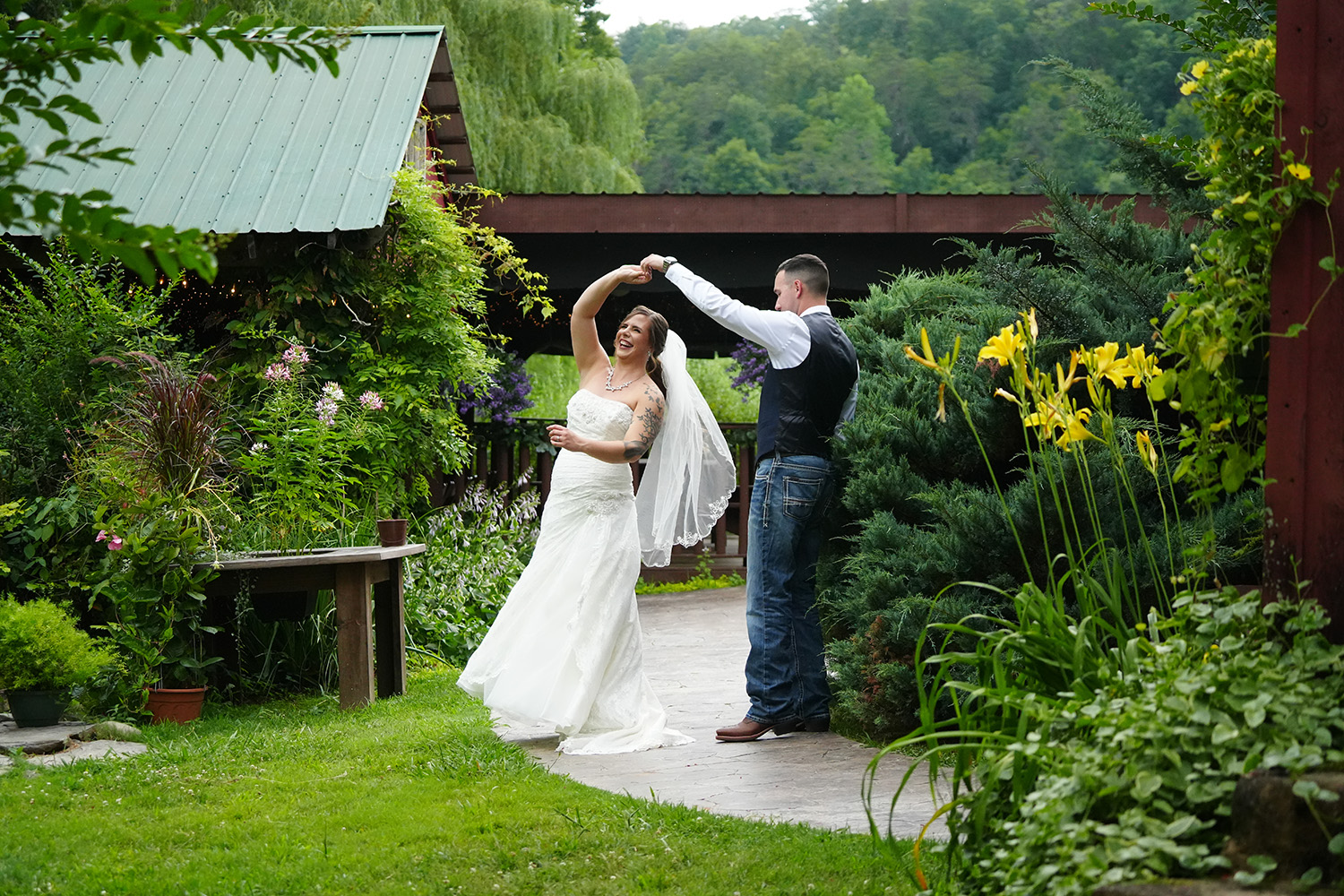 wedding couple dancing by a covered pavilion with yellow lilies