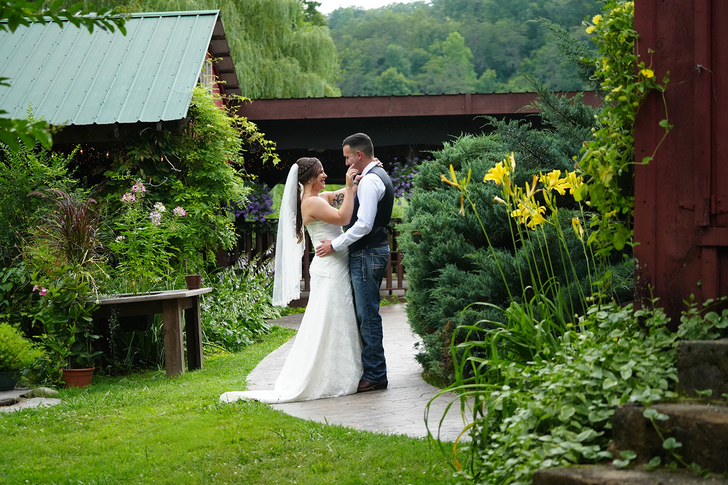 Wedding couple holding each other in a country garden by a rustic pavilion at Honeysuckle Hills in Pigeon Forge