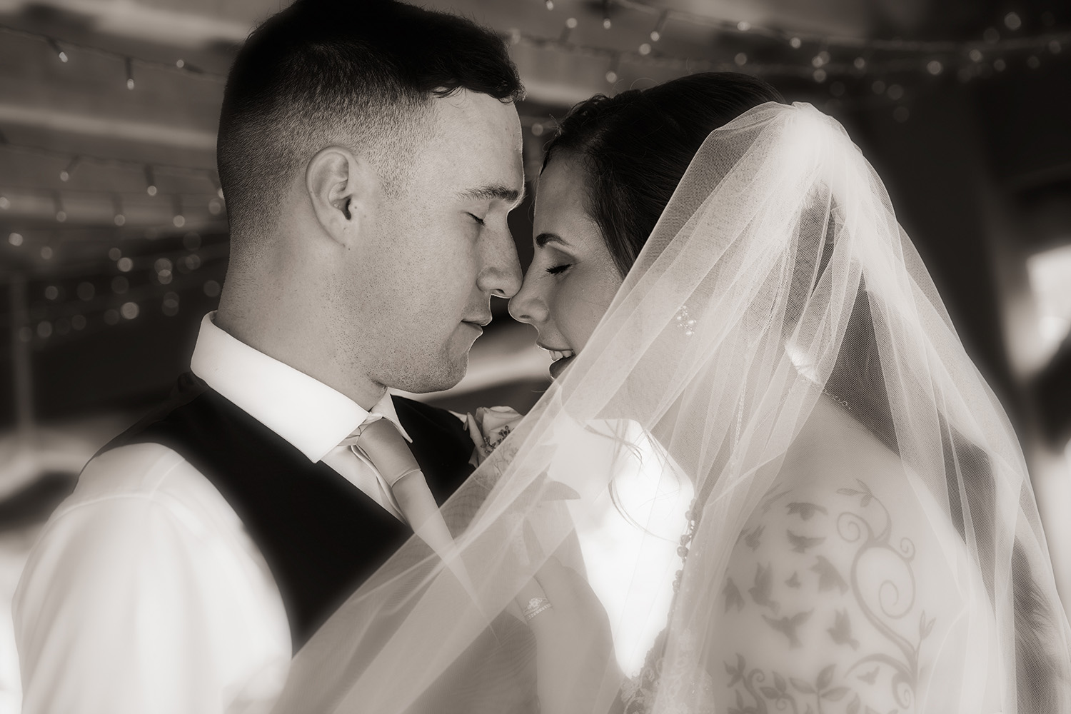 black and white portrait of a wedding couple with their foreheads touching and soft looks on their faces