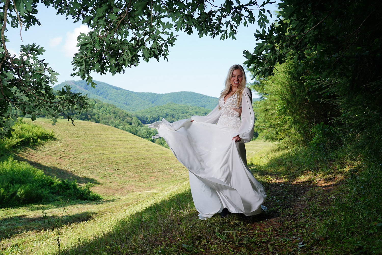 bride swishing her dress at a mountain view under trees in the summer
