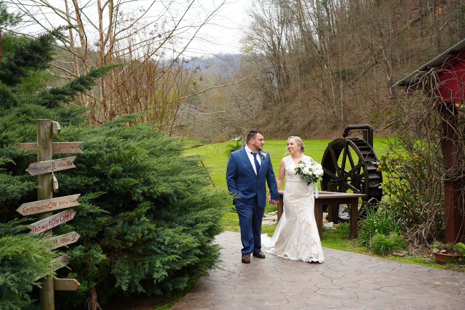 Couple walking on their wedding day by a water wheel at the Honeysuckle Hills wedding venue in Pigeon Forge