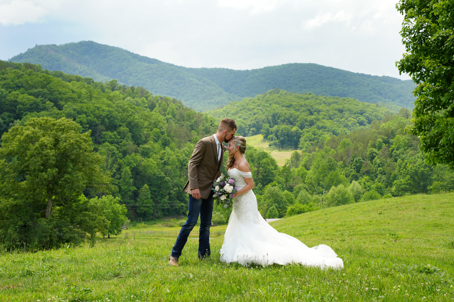 groom kissing his bride's forehead at a mountain view