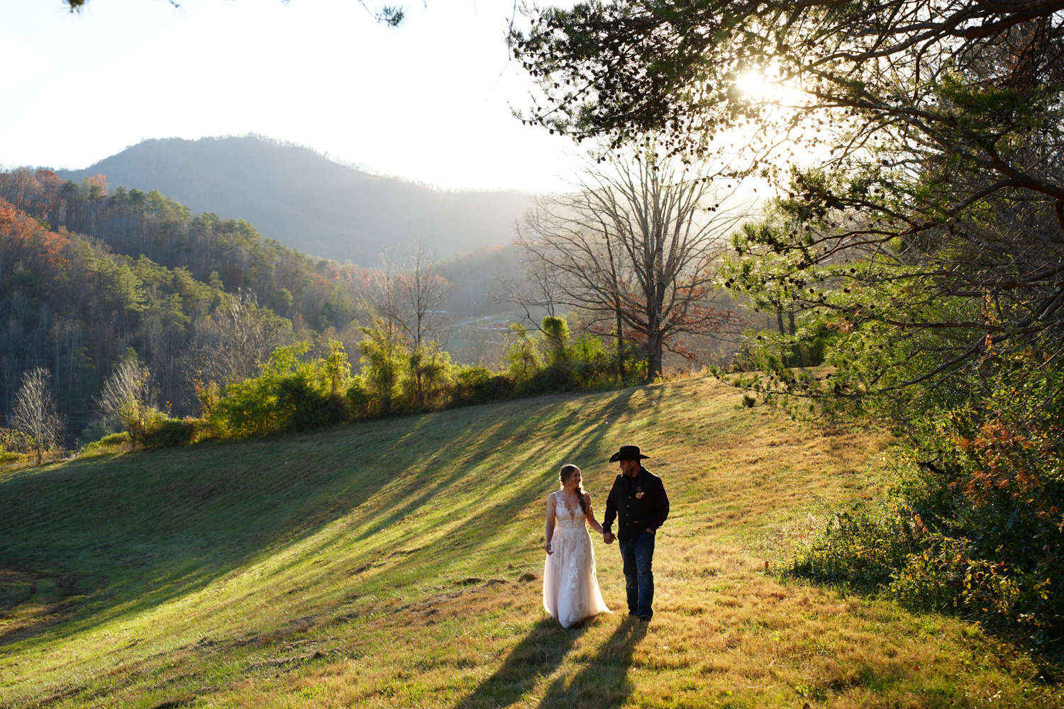 couple walking in a field toward a mountain view on their wedding day
