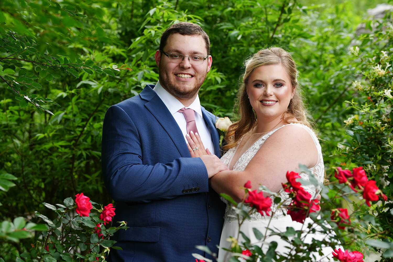 Wedding couple posing in front of red roses in the summer