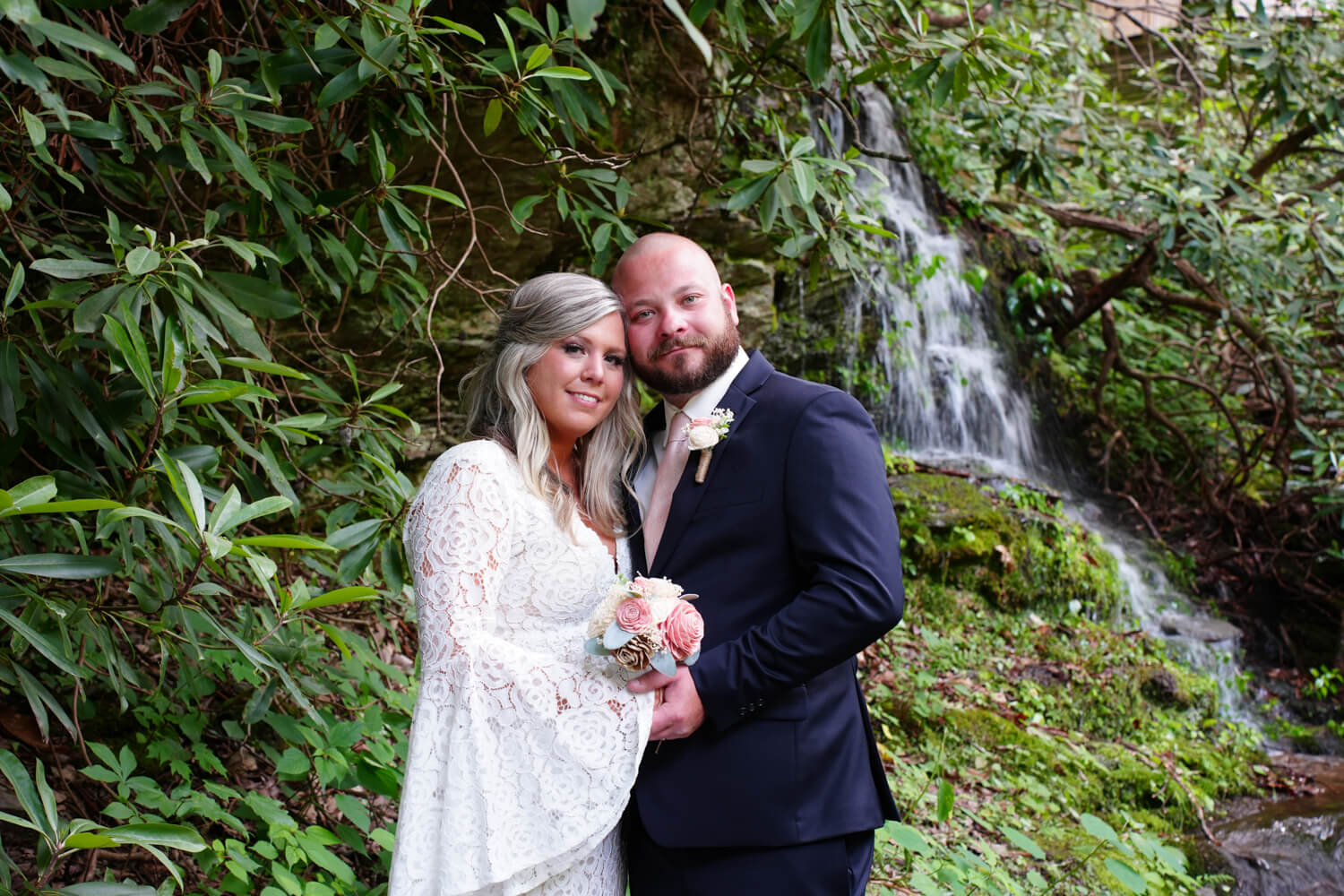Wedding couple holding hands with heads tilted together at a mountain waterfall in Pigeon Forge TN