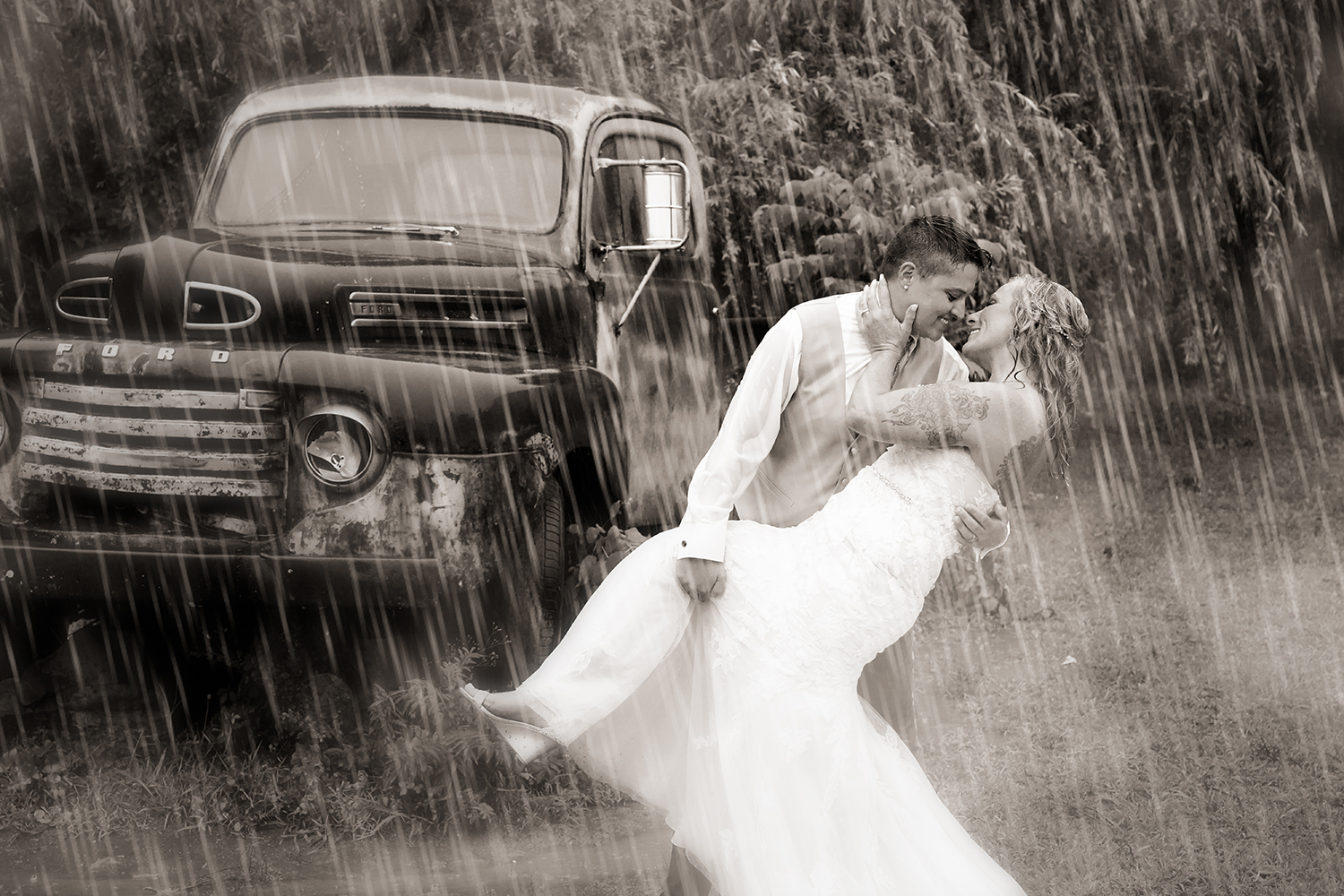 Bride dipping her bride by an old truck in the rain