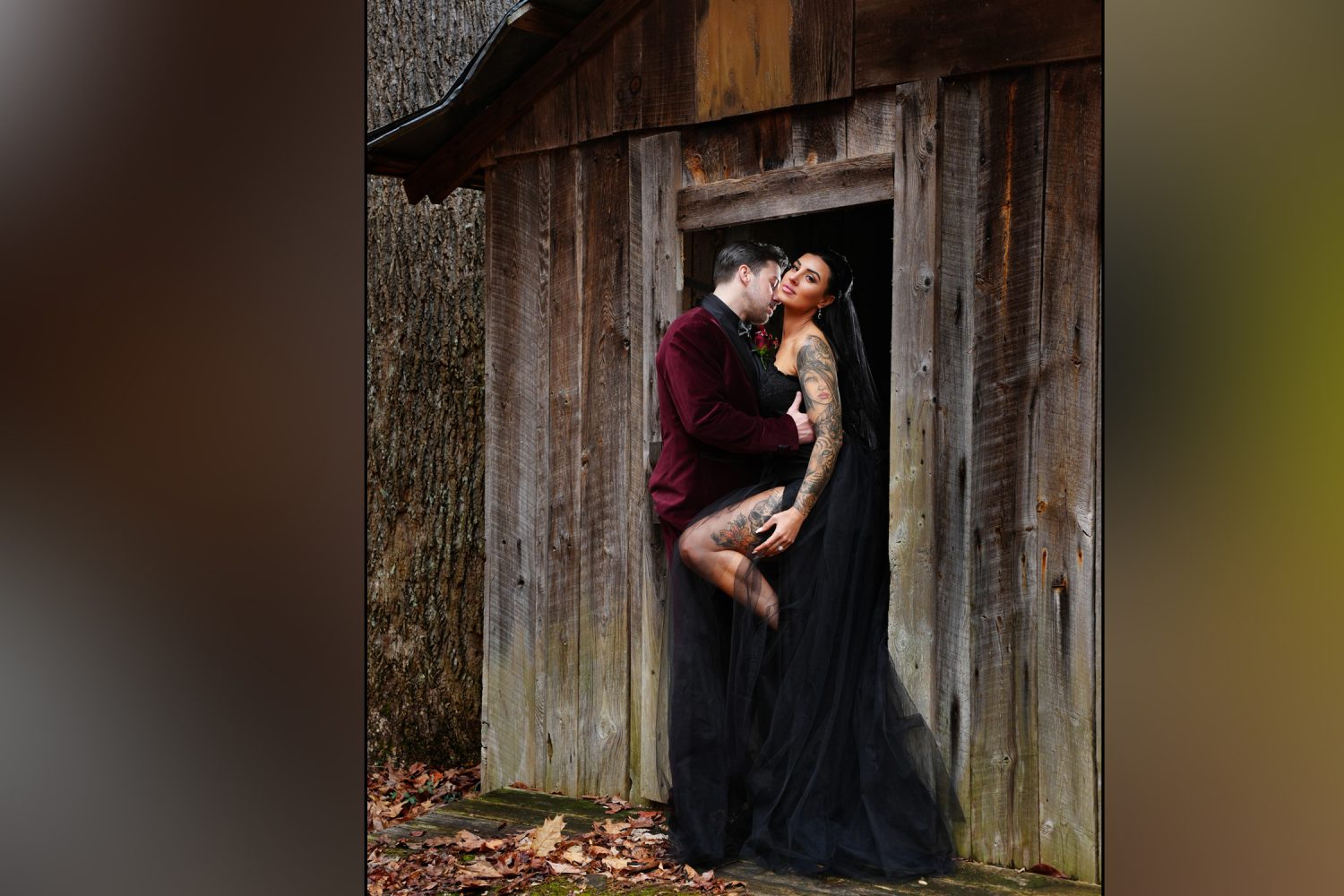 groom kissing a bride in a black wedding dress passionately against the door of an old smokehouse in the Smoky Mountains