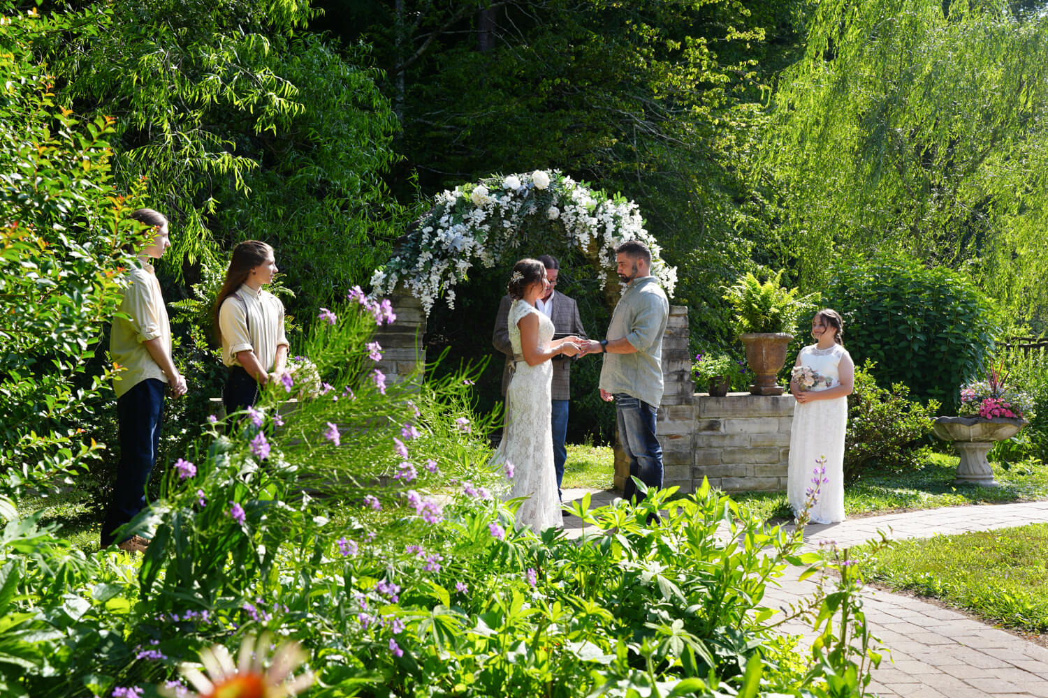 Micro wedding elopement ceremony at a stone arch with white flowers next to a garden with purple phlox and cone flowers at Honeysuckle Hills in Pigeon Forge