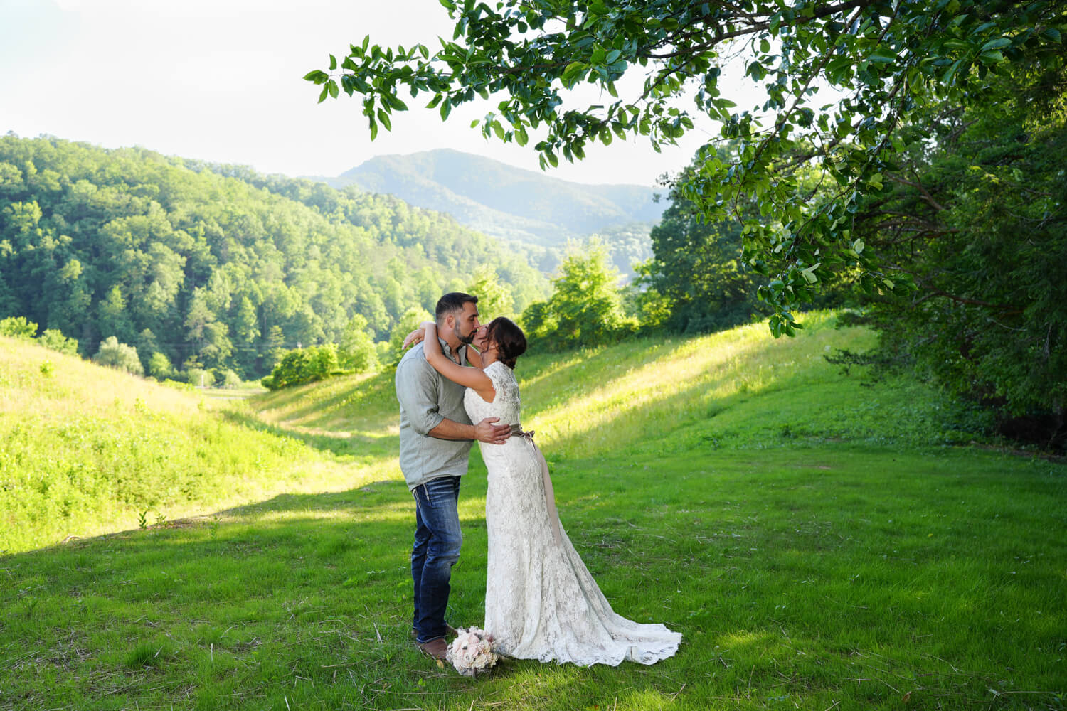 Bride arching upward to kiss her groom passionately at the mountain view ceremony site at Honeysuckle Hills in Pigeon Forge