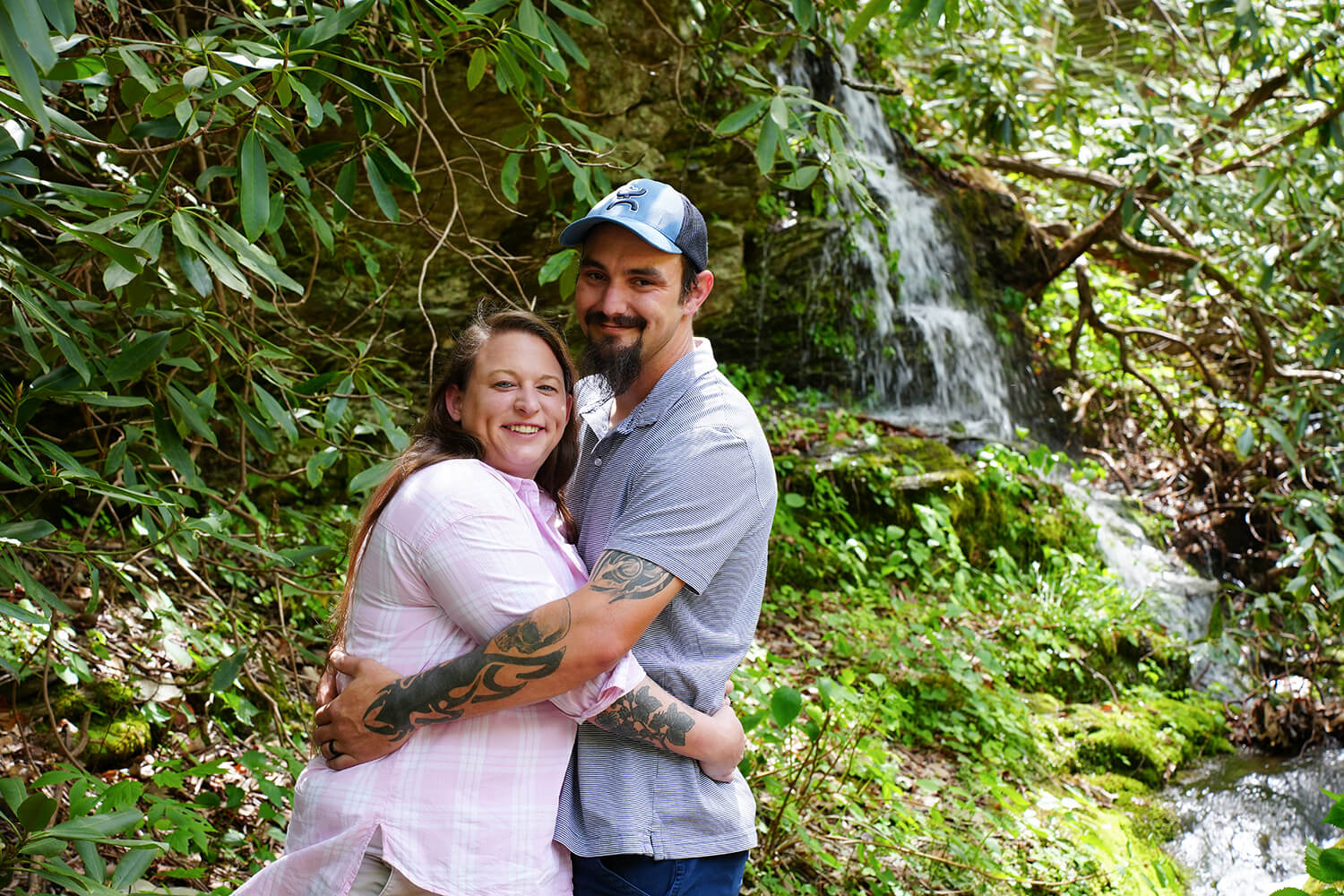 casually dressed wedding couple posing for a picture by the private mountain waterfall called Honeysuckle Falls near Gatlinburg