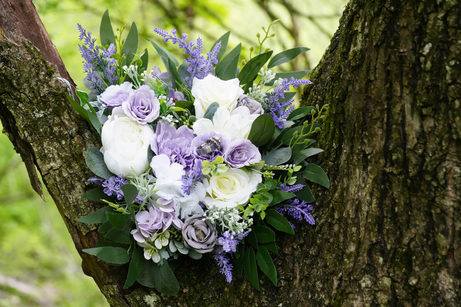 wedding bouquet with white and lavender flowers sitting in the fork of the willow tree branches at Honeysuckle Hills in Pigeon Forge
