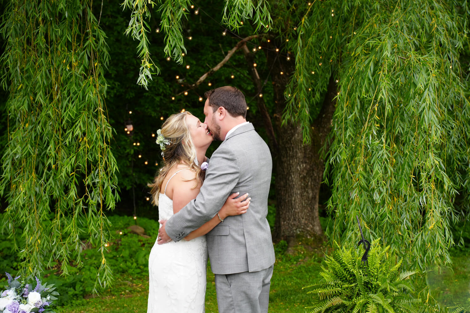 Bride and groom kissing joyfully under the willow tree at Honeysuckle Hills in Pigeon Forge on their wedding day