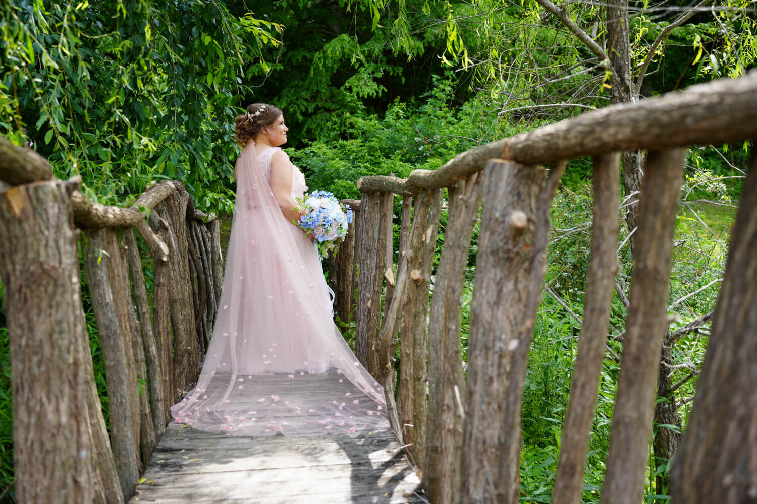 Bride on a bridge made from tree limbs in the forest at Honeysuckle Hills in Pigeon Forge