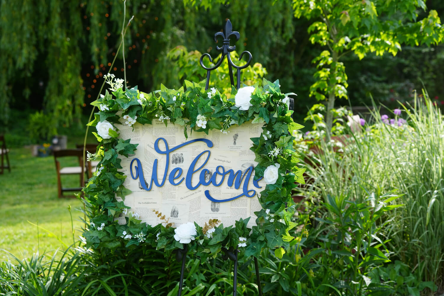 Wedding welcome sign made of book pages encircled with greenery on an easel by a willow tree at Honeysuckle Hills in Pigeon Forge