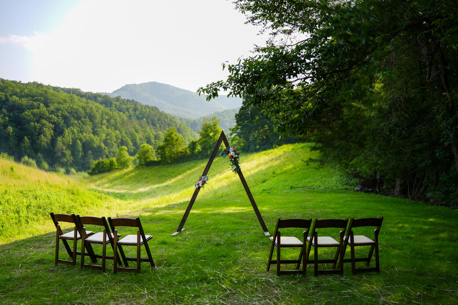 Mountain meadow ceremony location with dark wooden folding chairs and a triangle arbor at Honeysuckle Hills in Pigeon Forge TN