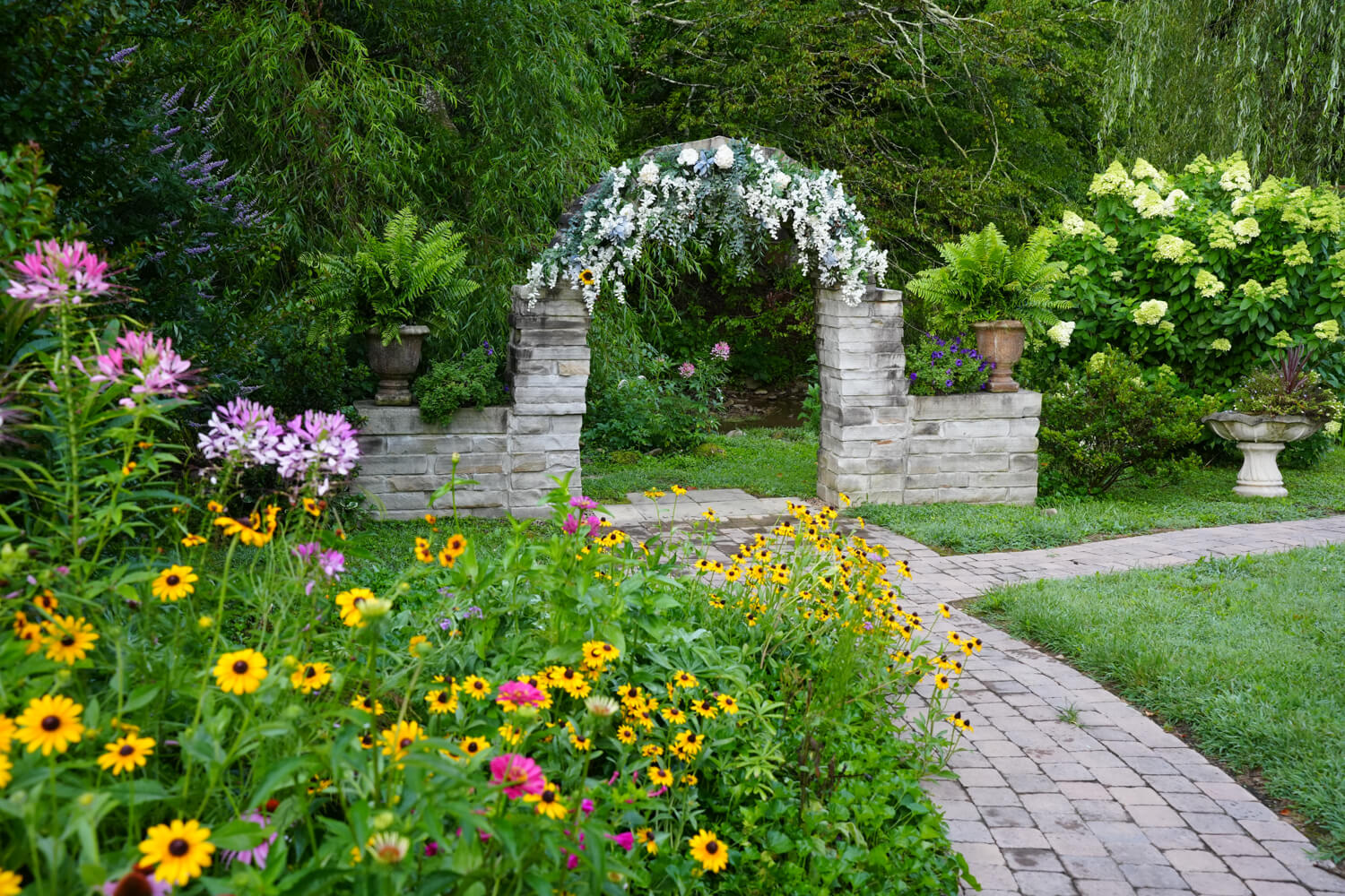 Stone arch wedding ceremony site in the wildflower garden with yellow rudbekia and pink cleome at Honeysuckle Hills in Pigeon Forge
