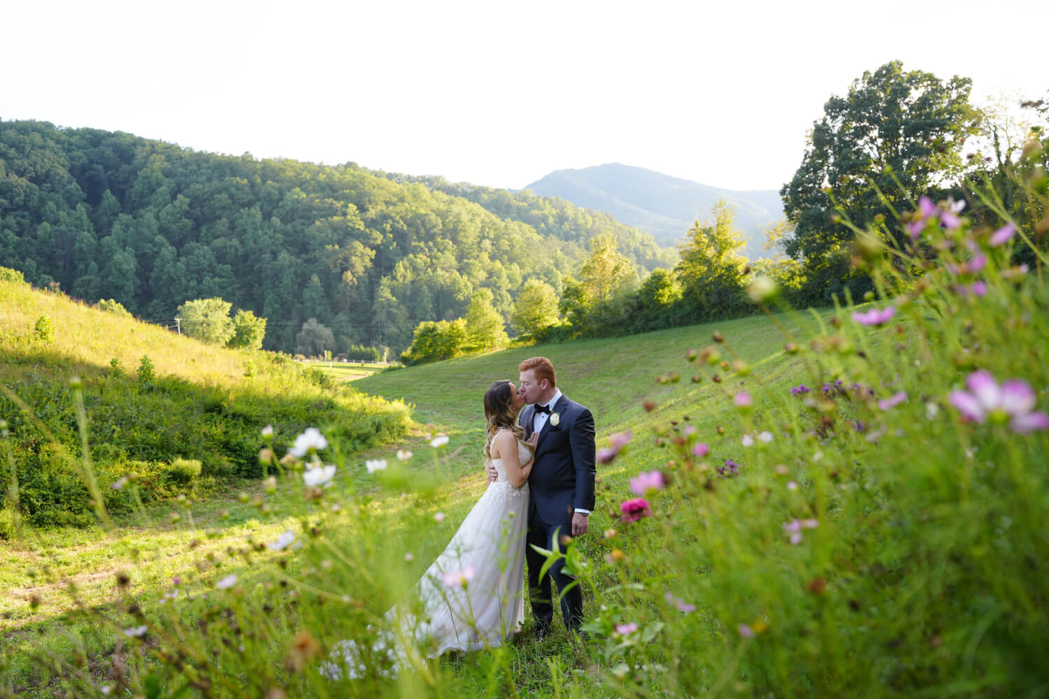 Wedding couple kissing in a field with wildflowers and a mountain view at Honeysuckle Hills in Pigeon Forge Tennessee