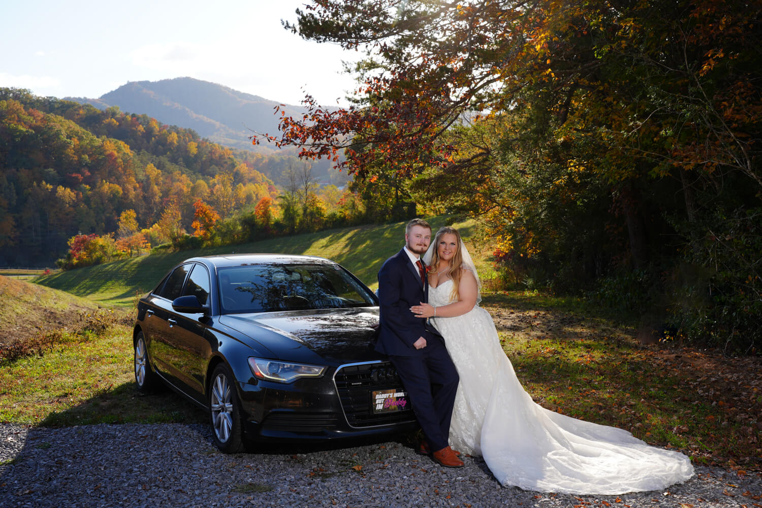 Wedding couple standing next to their black car by a field with a mountain view ceremony site at Honeysuckle Hills in Pigeon Forge Tennessee