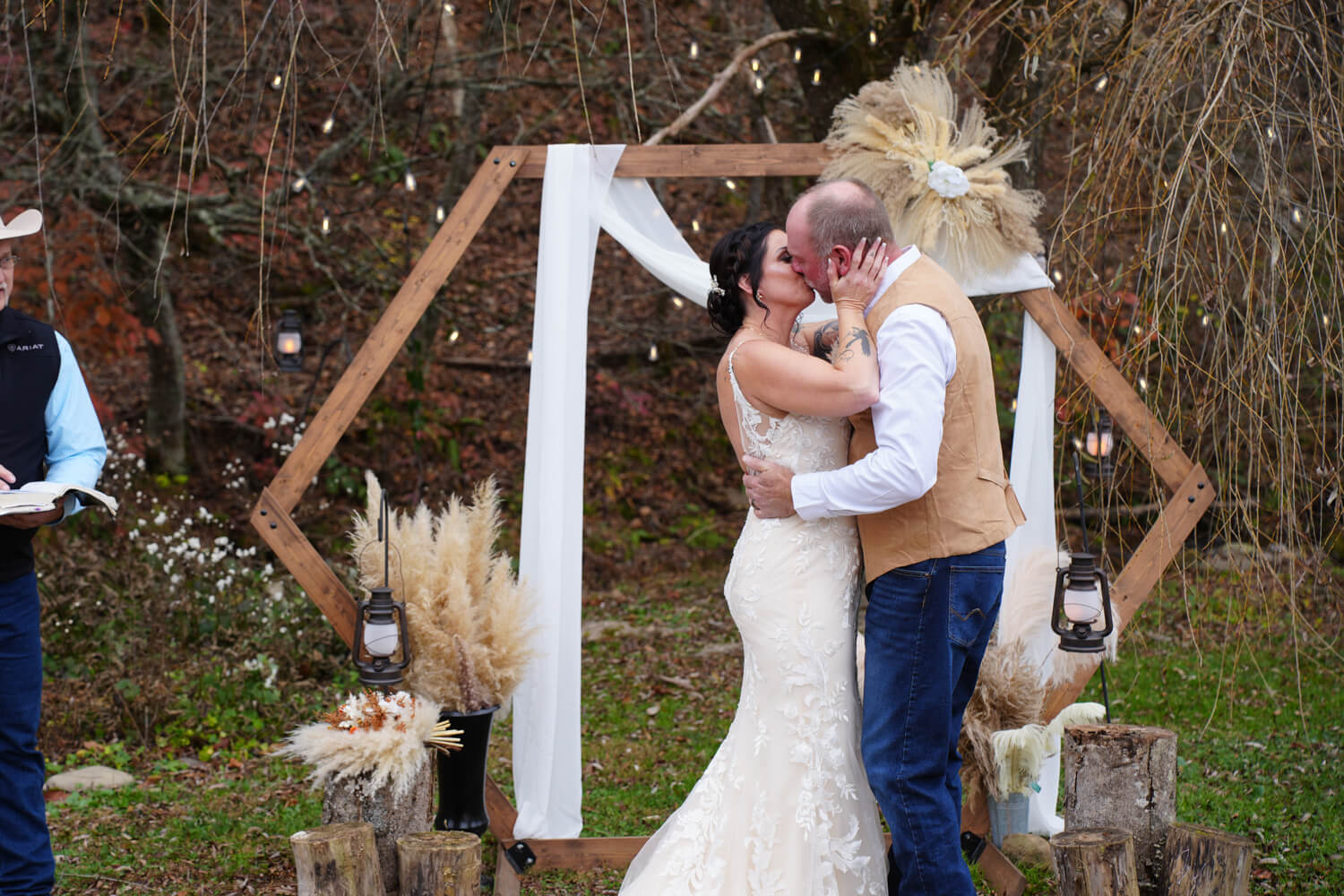 Wedding couple kissing in front of a hexagon arbor decorating with pampas grasses boho style