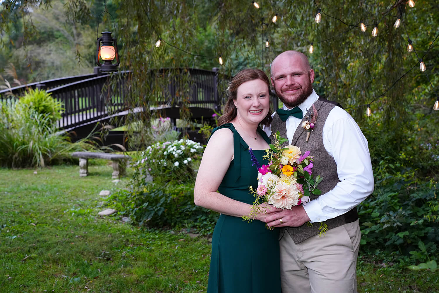 Elopement wedding with bride in simple green dress at a willow tree with fairy lights