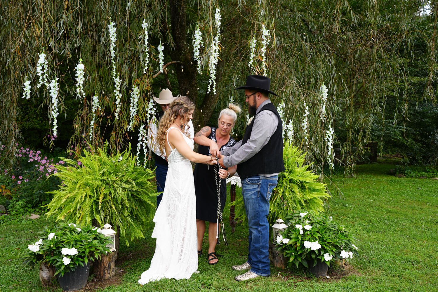 Western style hand fasting ceremony under a willow tree with white wisteria