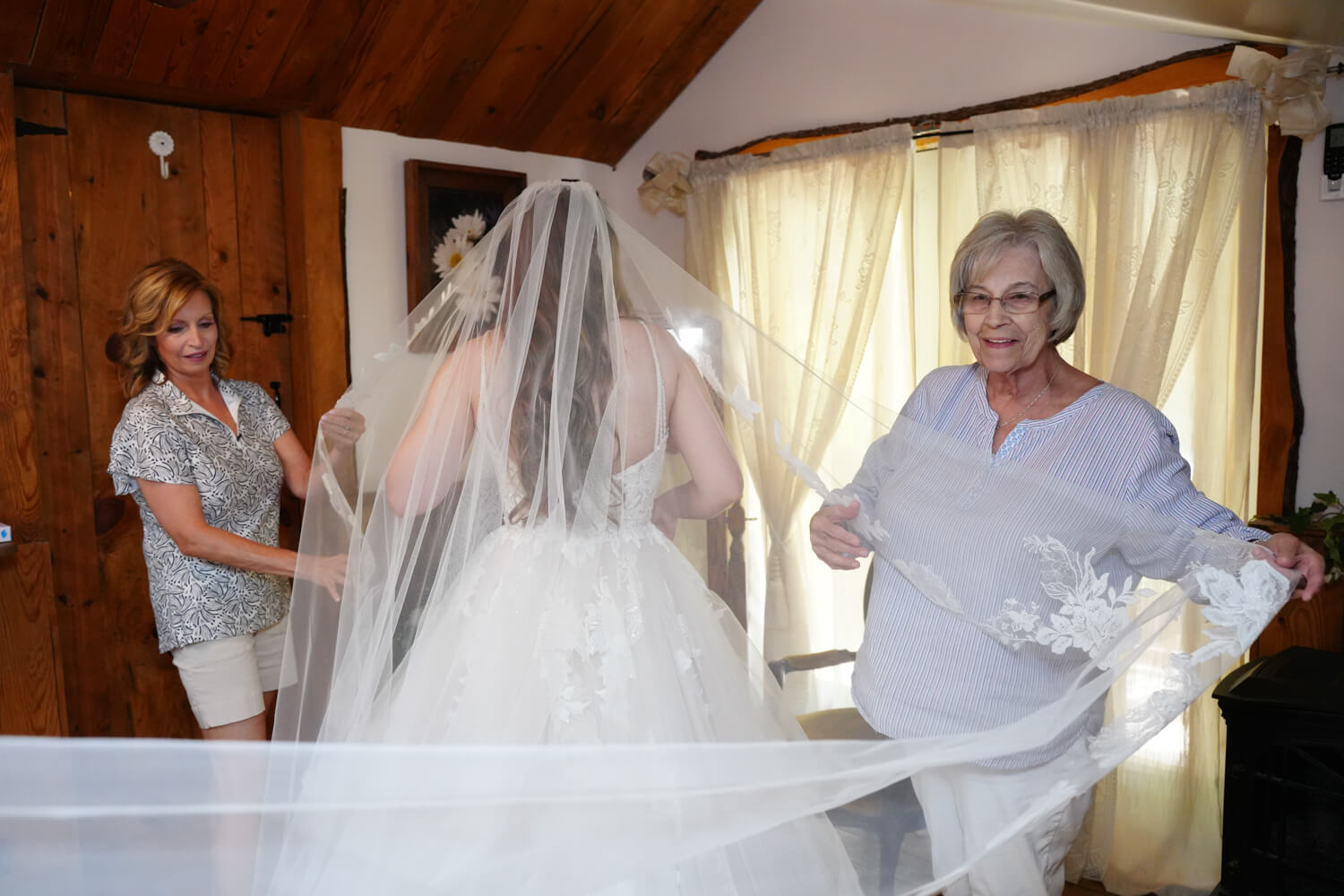 Grandmother fixing a bride's veil in the dressing area of a barn wedding venue in Pigeon Forge