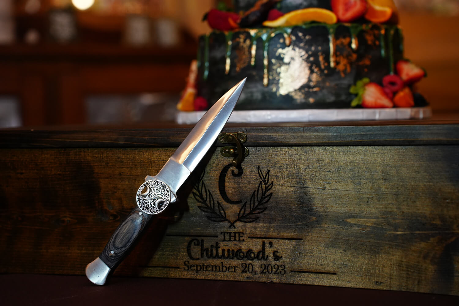 Wedding Cake knife with Celtic design leaning against a custom wooden cake box with the name and date of the wedding couple