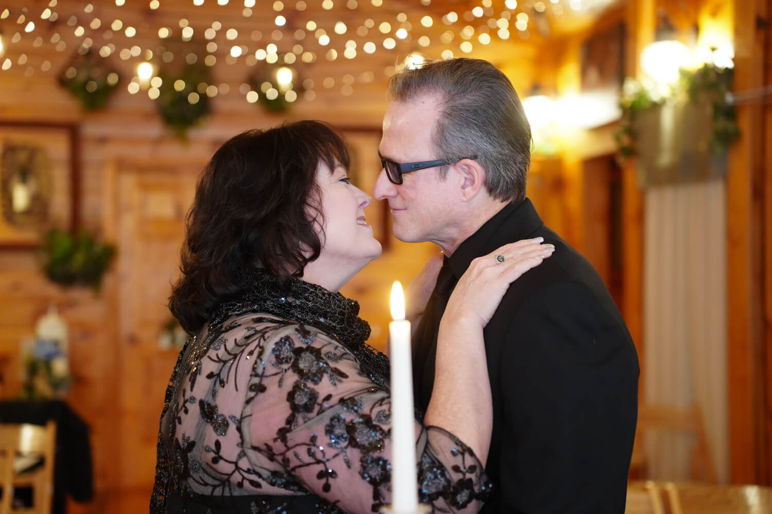 Wedding couple kissing in front of a candle in a wedding chapel with string lights on the ceiling
