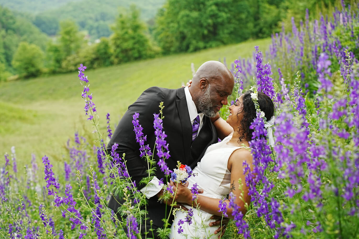 Groom leaning his bride back into a meadow of purple larkspur wildflowers in the Smoky Mountains