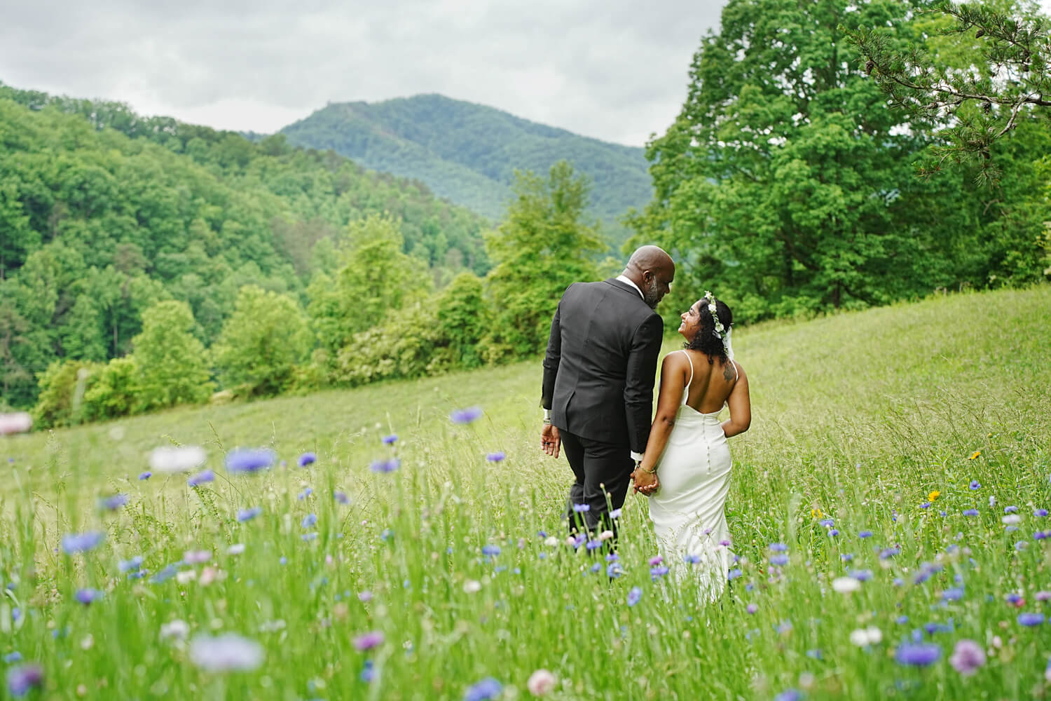 couple walking in a field of purple and pink spring wildflowers in the mountains of Pigeon Forge