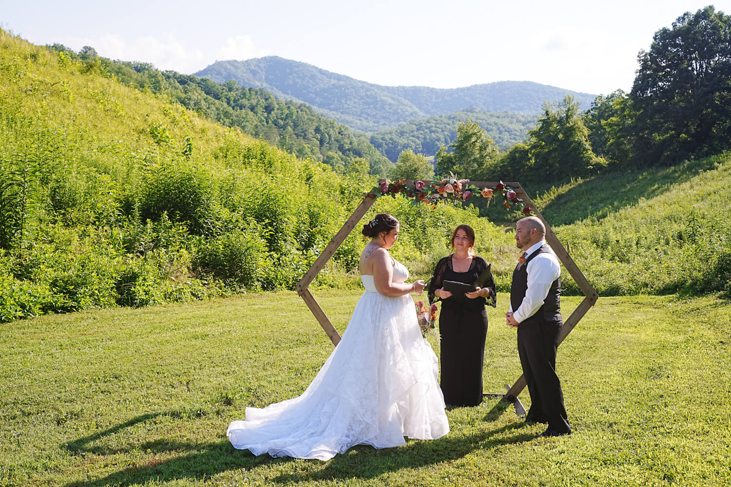 Wedding ceremony at a mountain view in a field with a hexagon arbor