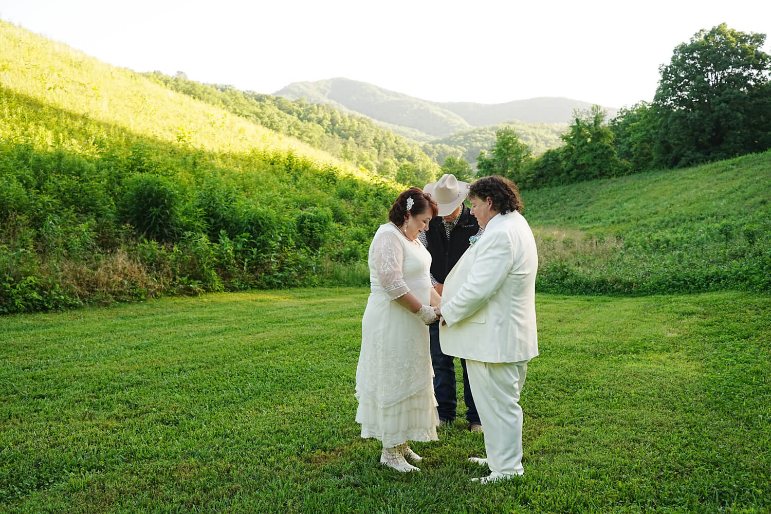 Couple getting married in a meadow with a mountain view