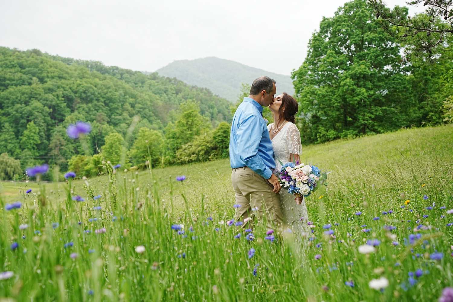 couple kissing in a field of wildflowers on their wedding day at a mountain view