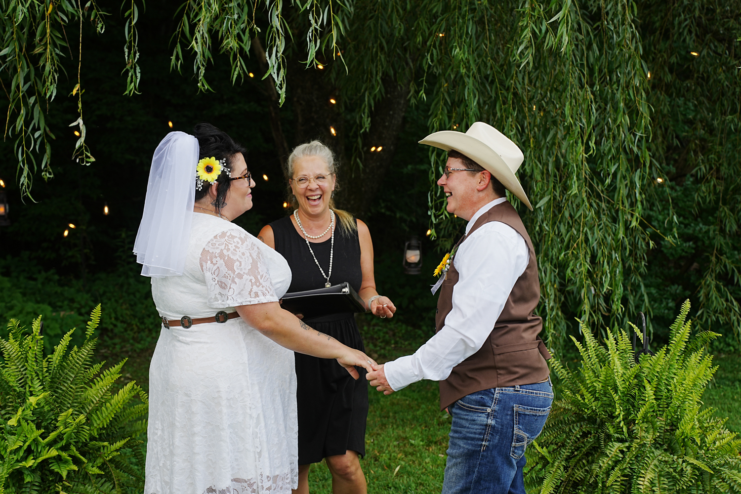 Two brides in a same sex LGBTQ wedding under a willow laughing and enjoying sharing their vows at Honeysuckle Hills in Pigeon Forge