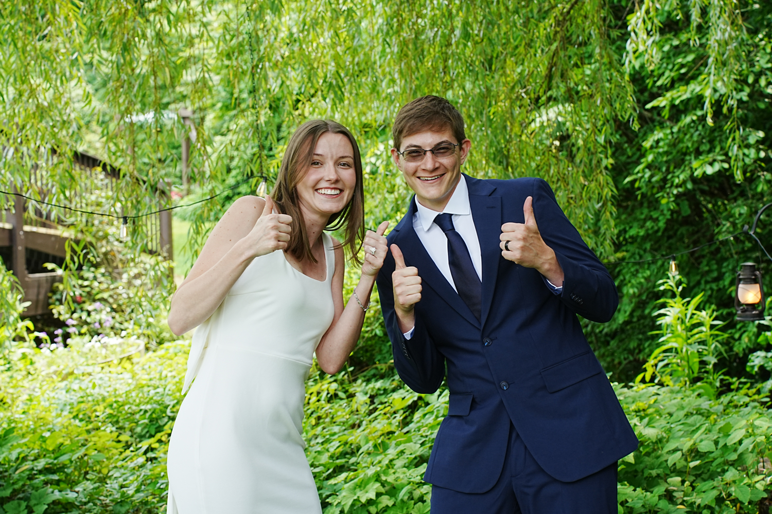 Wedding couple holding their thumbs up after their ceremony under a willow tree at the Honeysuckle Hills wedding venue in Pigeon Forge