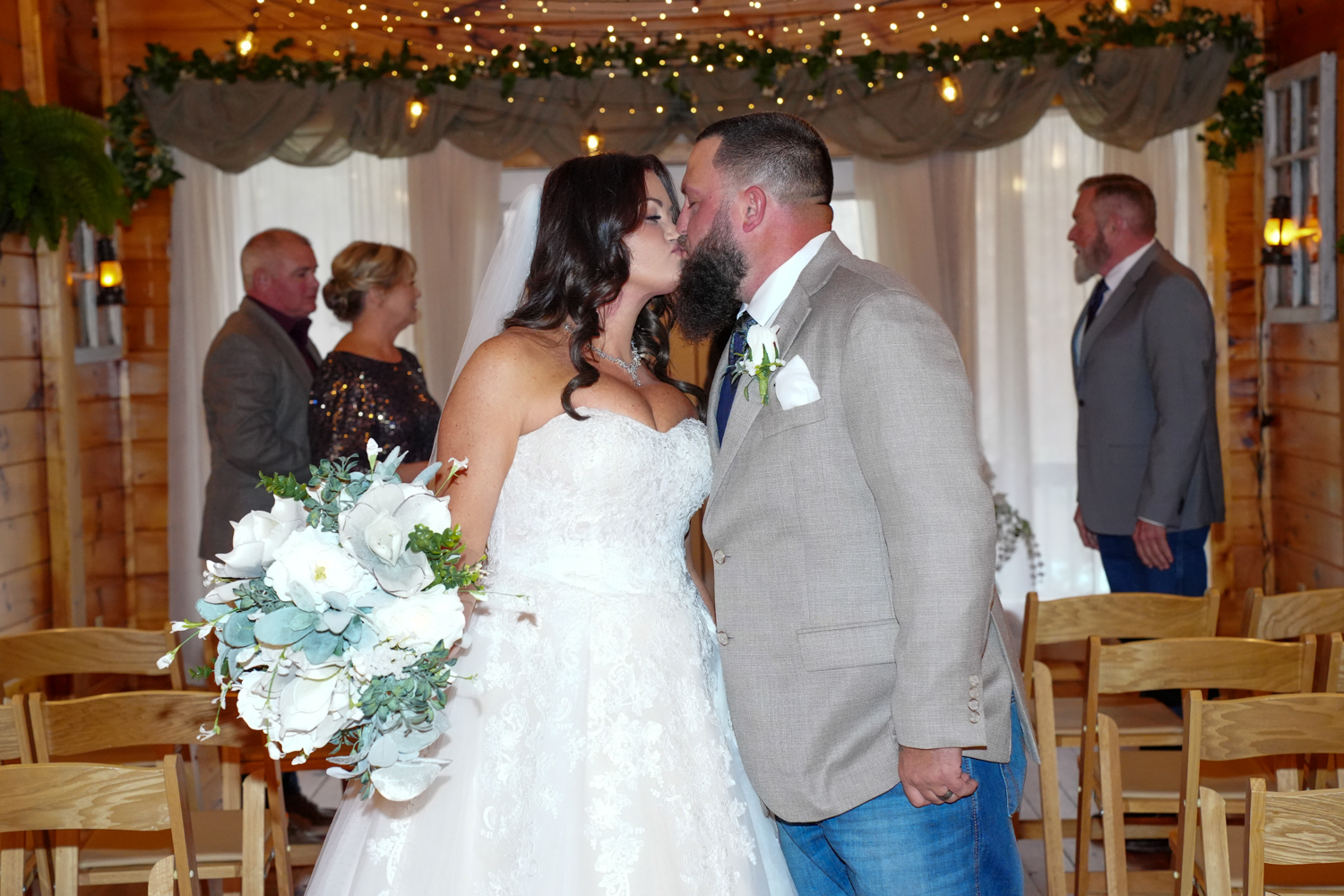 Couple kissing in a wedding chapel under warm twinkling lights