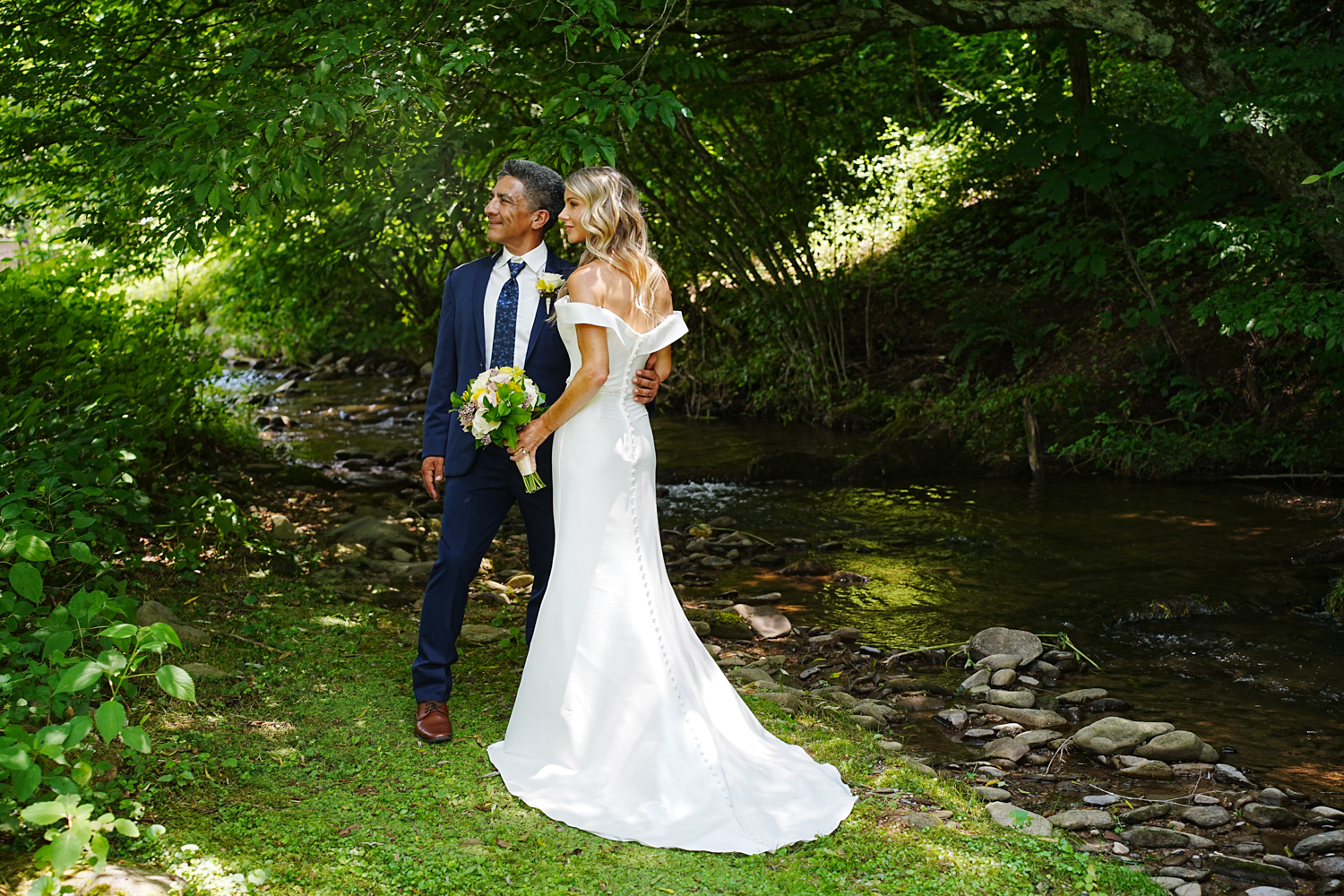 Formal wedding couple posing at a creek on their wedding day in Pigeon Forge