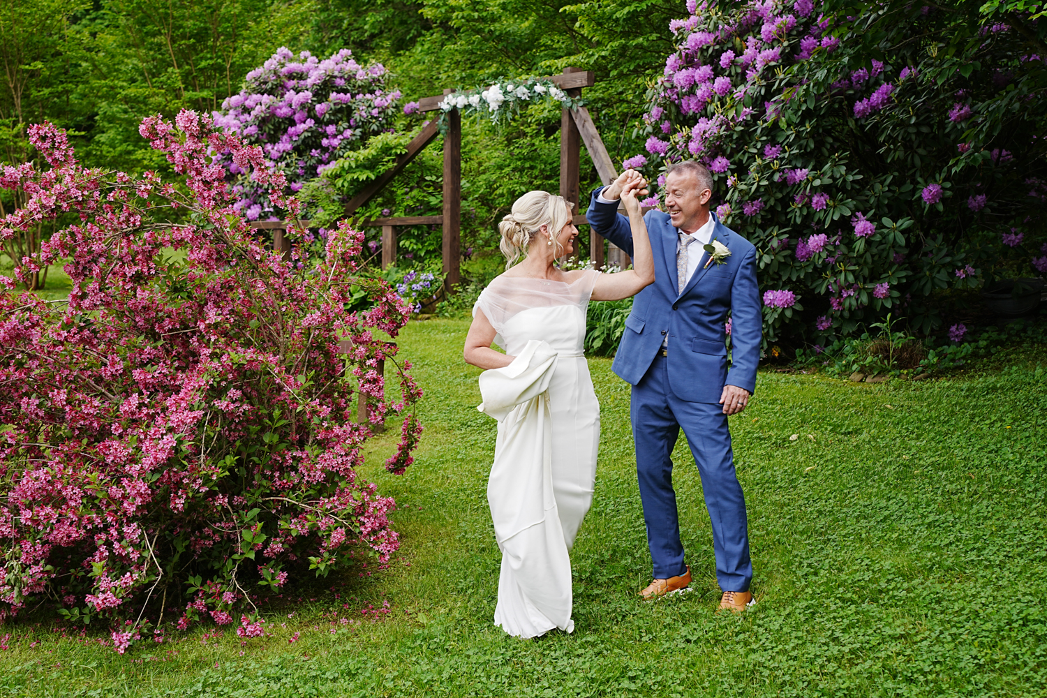 Bride dancing with her groom in a spring garden of pink blooming bushes at the Honeysuckle Hills wedding venue in Pigeon Forge