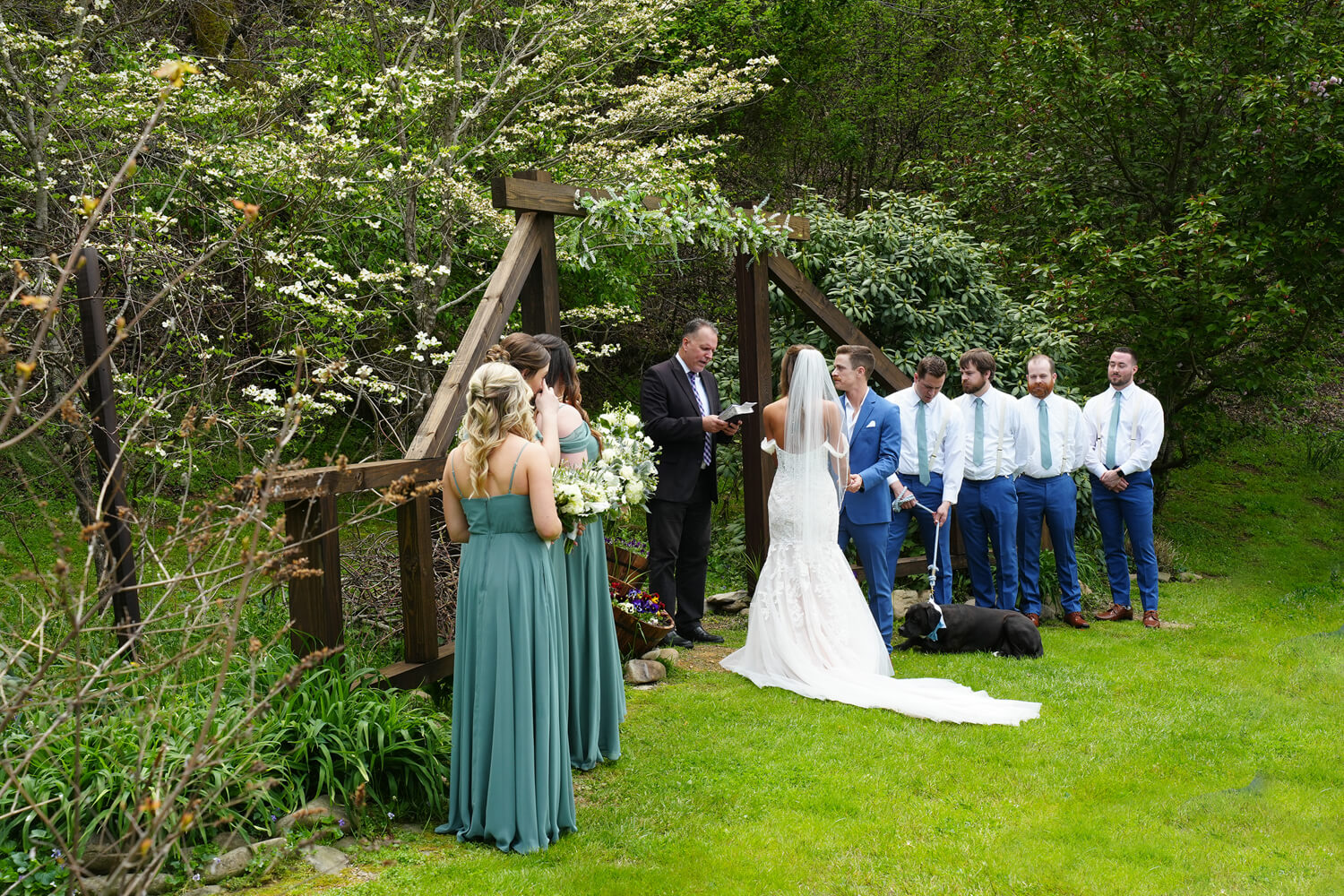 Early spring wedding with dogwood trees in bloom at a wooden wedding arbor