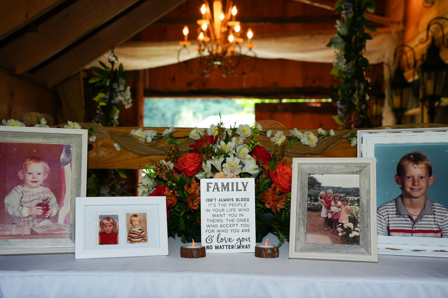 Wedding entry table set up with pictures under a chandelier in a barn wedding venue in Pigeon Forge Tennessee