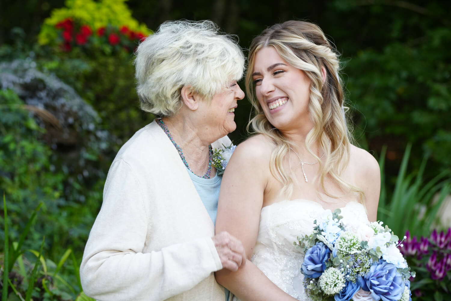 Bride and her grandmother smiling at each other while posing for family pictures at her wedding