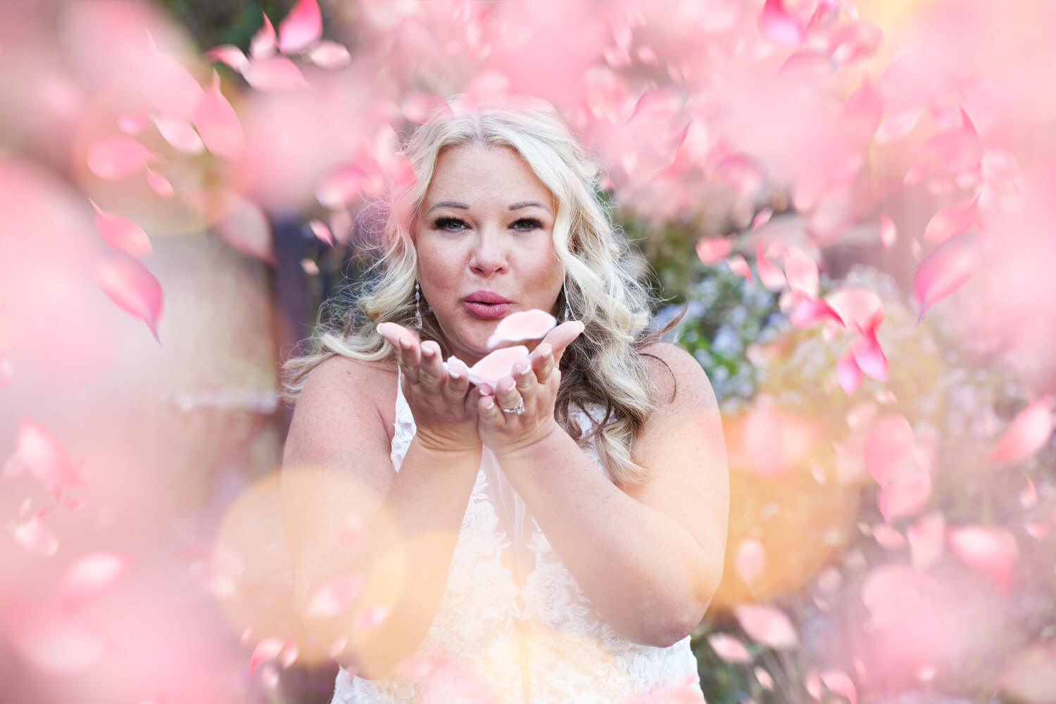 Bride blowing pink petals