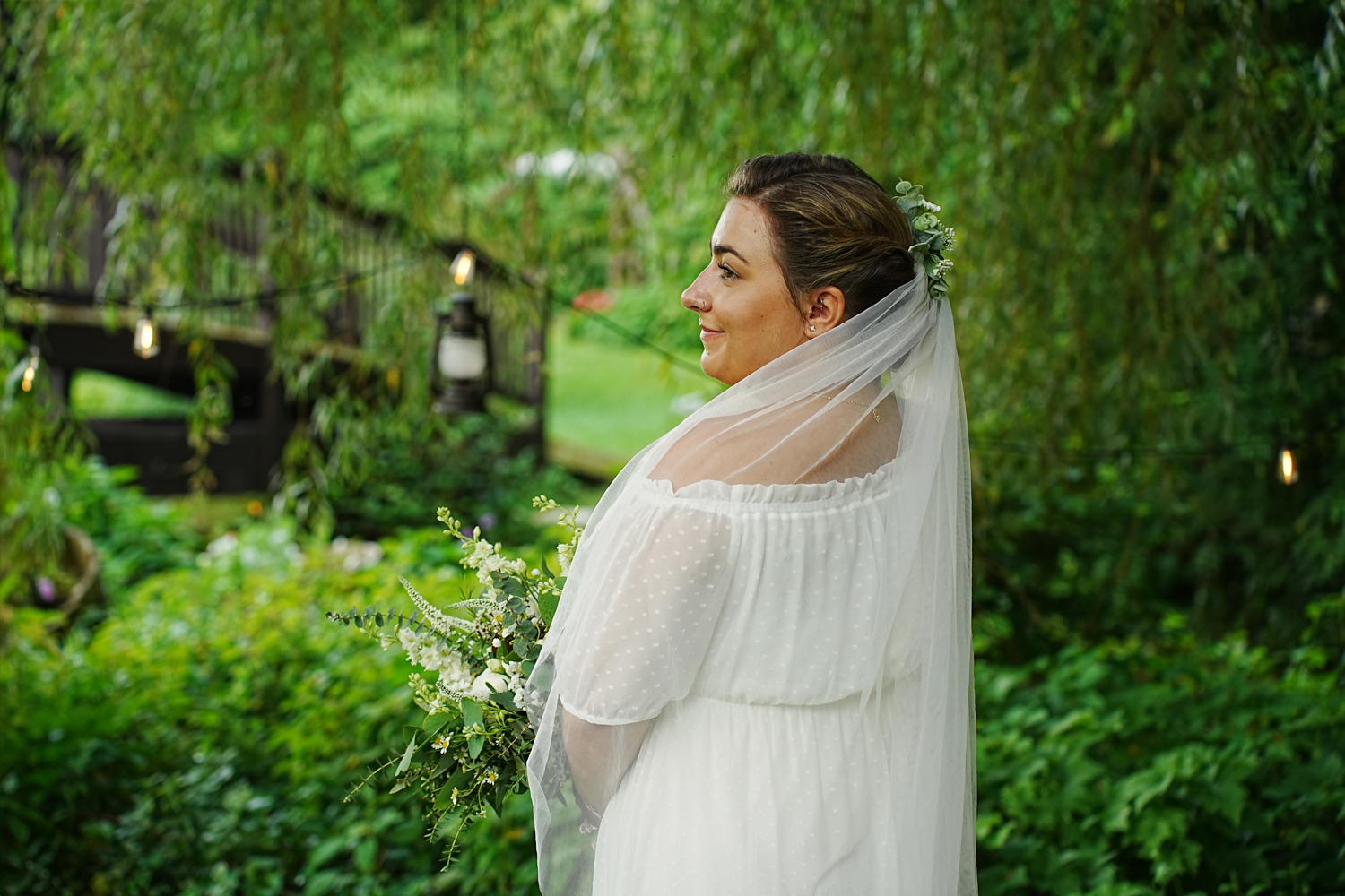 Profile portrait of a bride under a willow tree in the summer with her veil laying gently on her shoulder