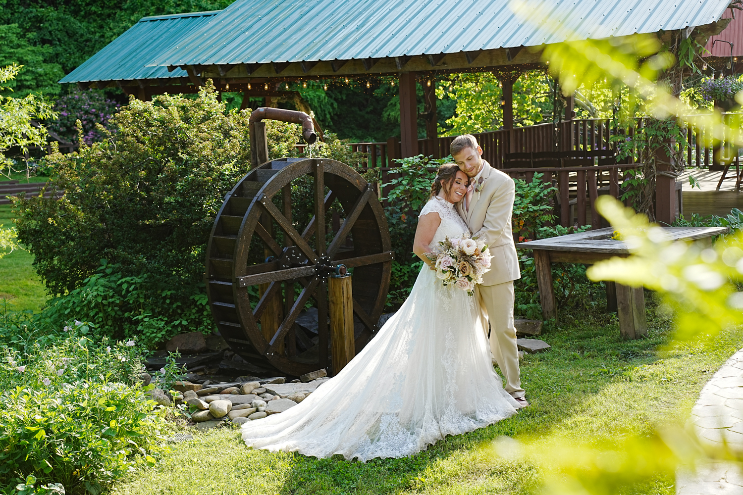 Informal wedding portrait in the summer next to a wooden water wheel at Honeysuckle Hills in Pigeon Forge