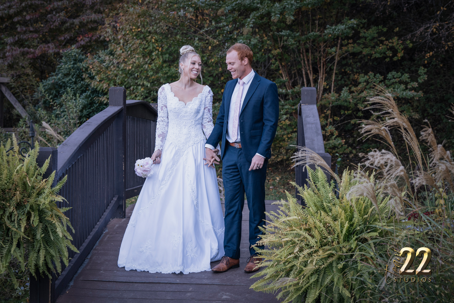Bride and groom walking across a bridge in the fall