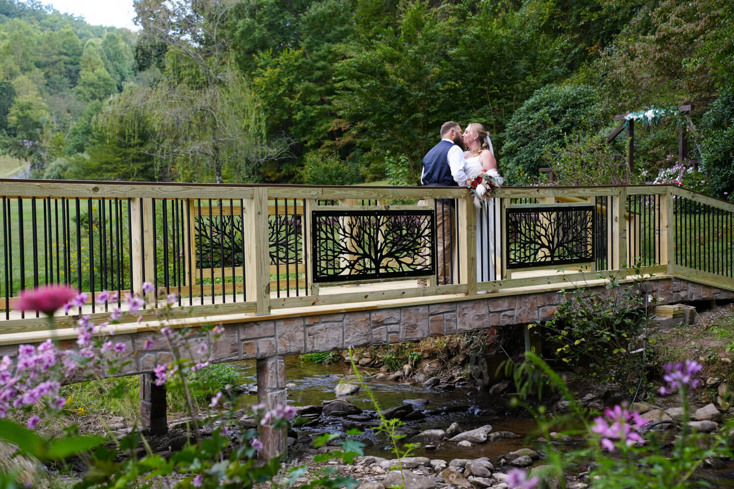 Bride and Groom kissing on a bridge with iron willow tree panels